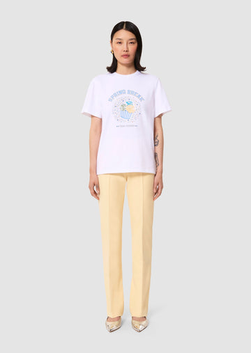 model wearing a white t-shirt with a graphic design and light-yellow pants on a plain background