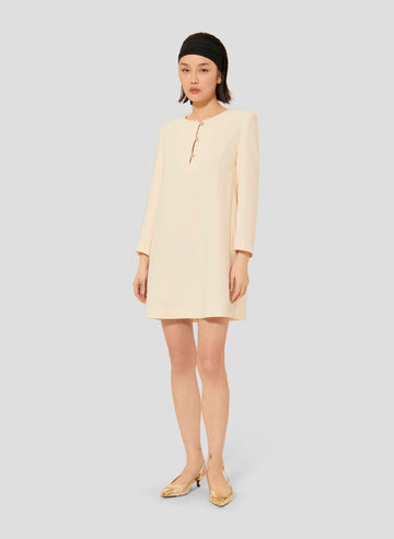 Model wearing Tara Jarmon short ecru crepe dress with long sleeves and a round neckline.