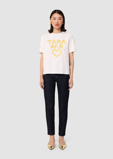 Woman wearing a white t-shirt with 'TARA PAR' text and denim pants on a white background