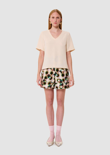 Woman wearing an ecru crepe t-shirt and patterned shorts on a white background