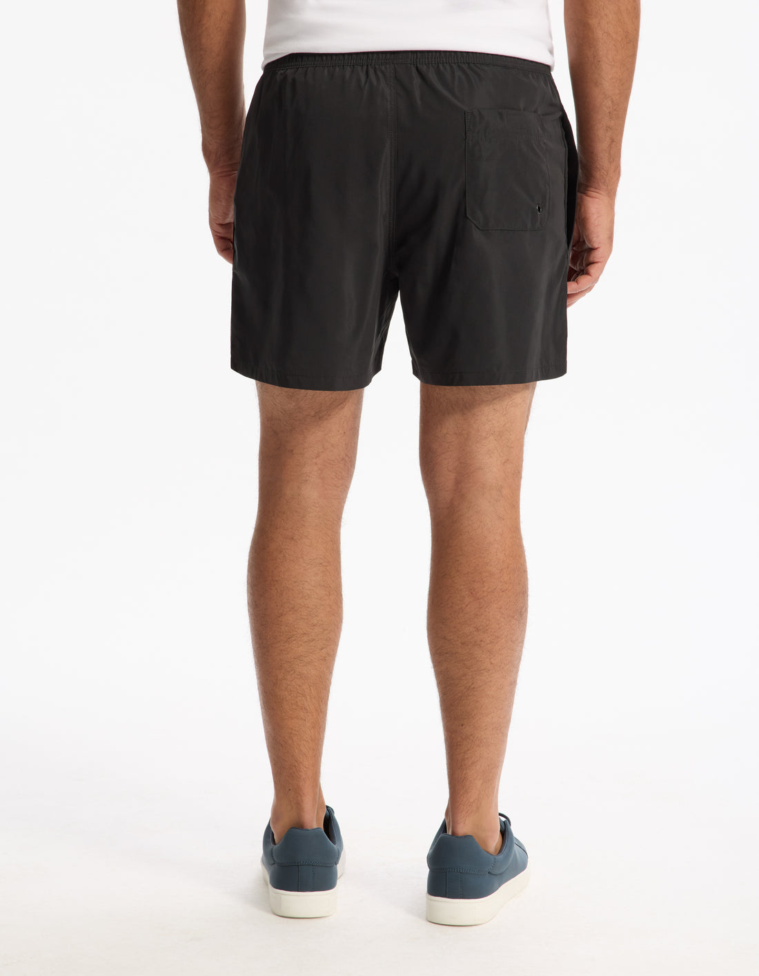 Model wearing black shorts and blue sneakers on a white background