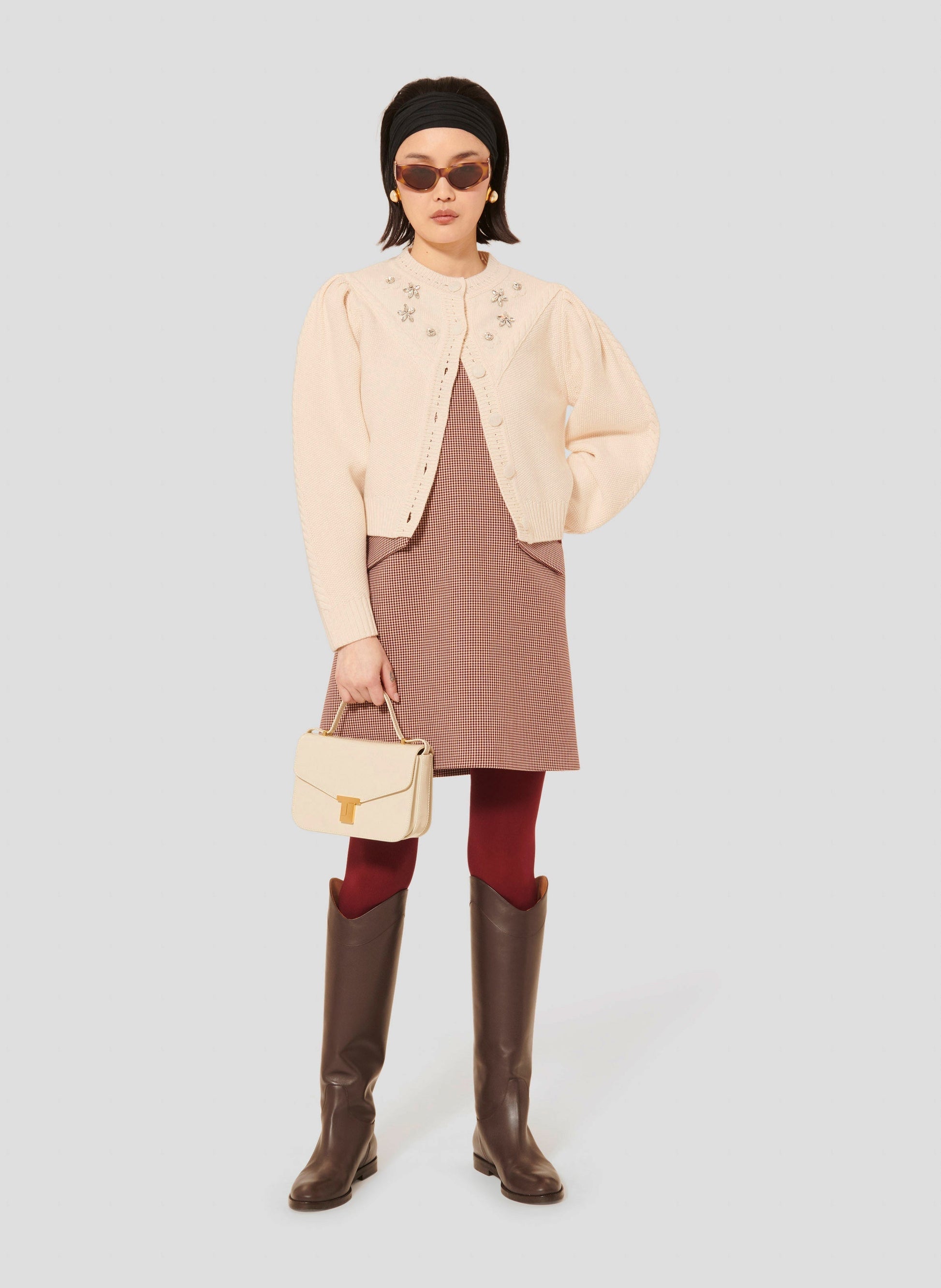 Tara Jarmon model wearing ecru
cardigan in merino wool on top of a burgundy houndstooth dress