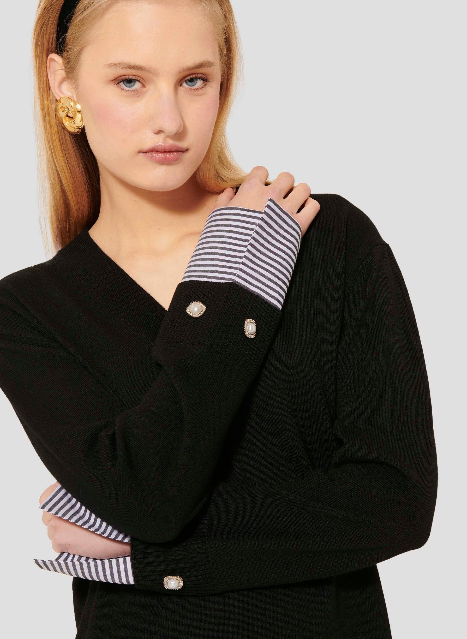 Stylish Model Wearing a Black V-Neck Sweater with Gingham Cuffs.