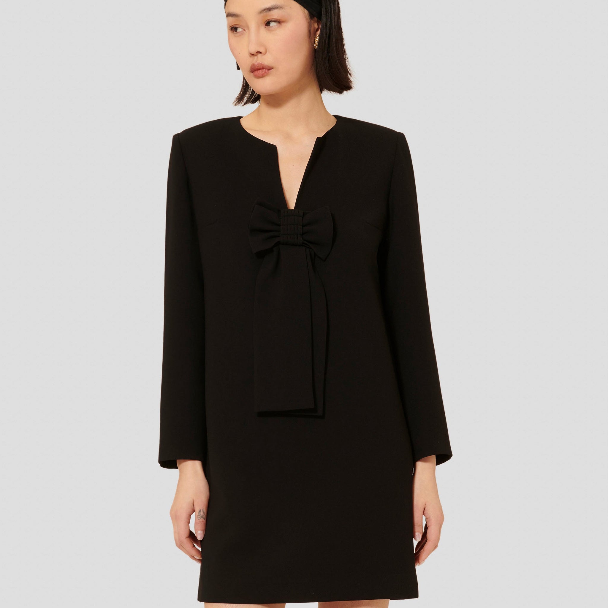 Model wearing Tara Jarmon Women's Black Crepe Dress with V-Neck and Long Sleeves.