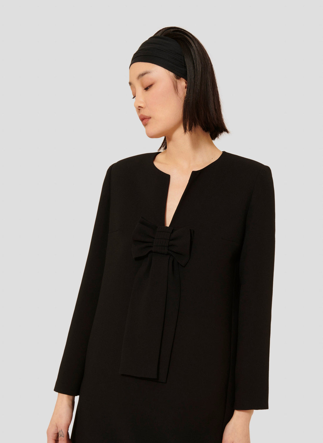 Model wearing Tara Jarmon Women's Black Crepe Dress with V-Neck and Long Sleeves.