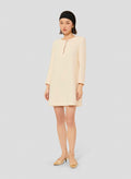 Model wearing Tara Jarmon short ecru crepe dress with long sleeves and a round neckline.