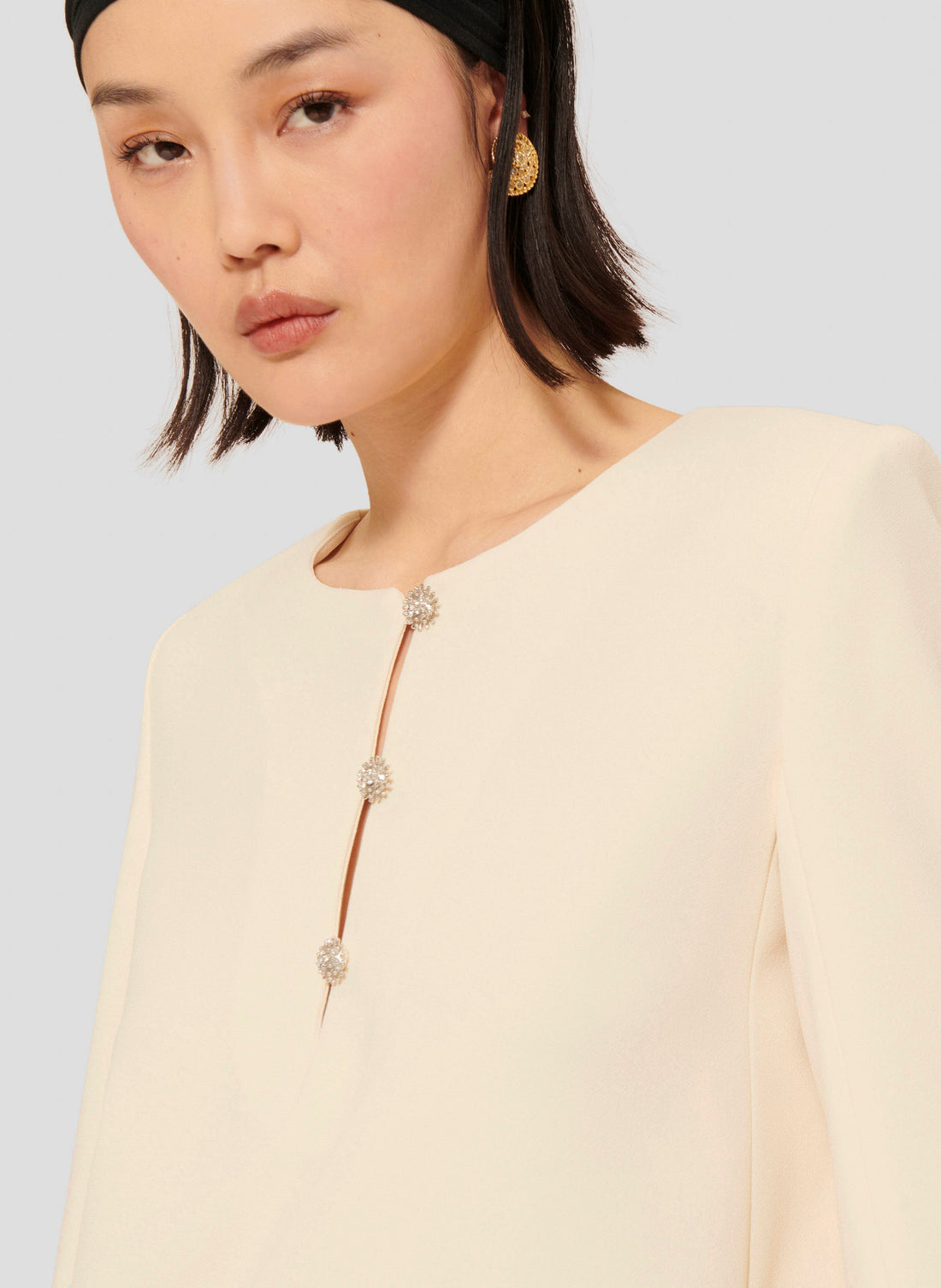 Model wearing Tara Jarmon short ecru crepe dress with long sleeves and a round neckline.