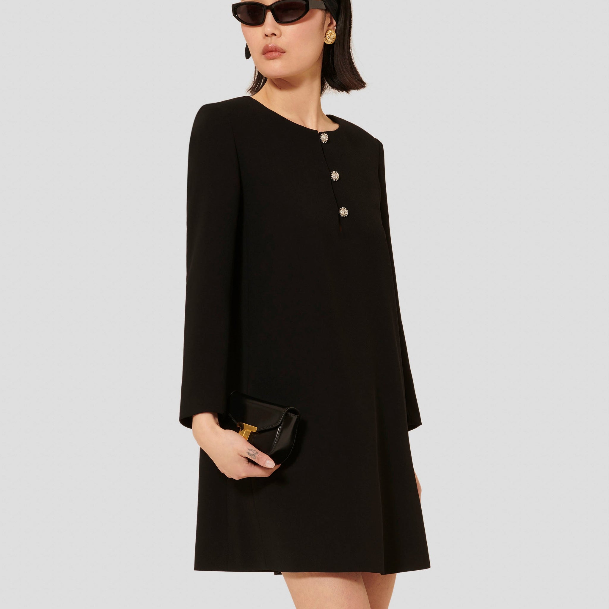 Model wearing Tara Jarmon short black crepe dress with long sleeves and a round neckline.