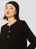 Long sleeves black dress with round neckline and gold buttons. 