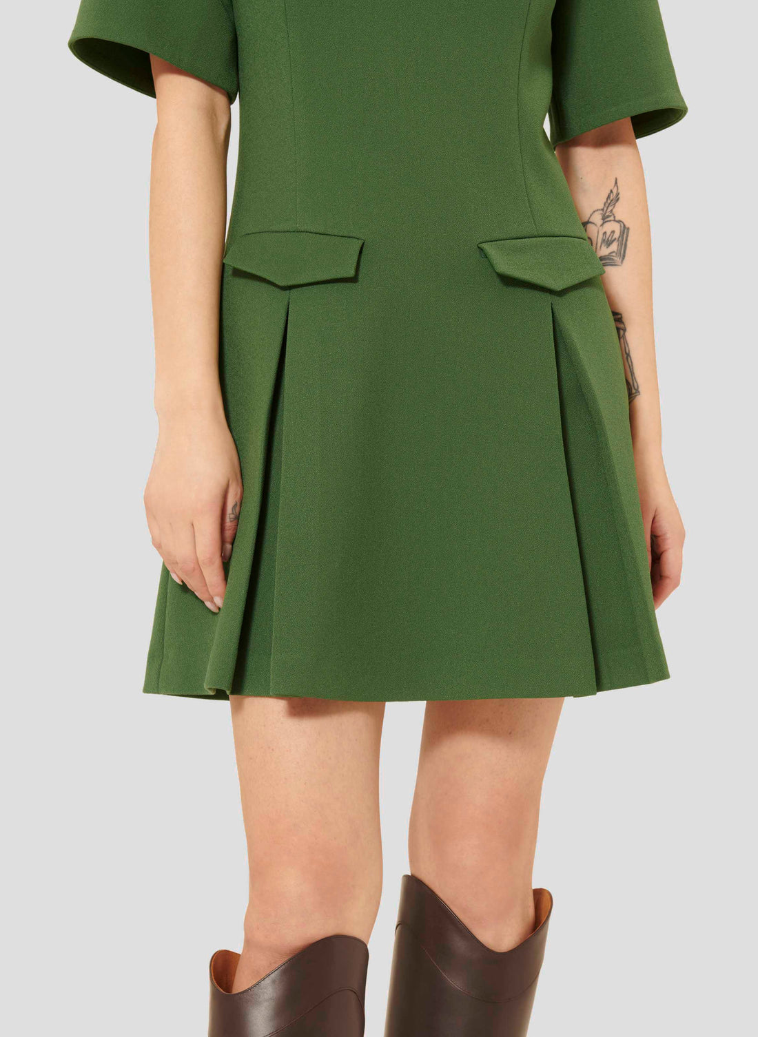 Model wearing Tara Jarmon Green Crepe Short Dress with Pleated Skirt and Flap Pockets.