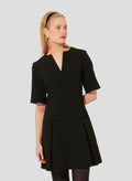 Model wearing Tara Jarmon Black Crepe Short Dress with Pleated Skirt and Flap Pockets.