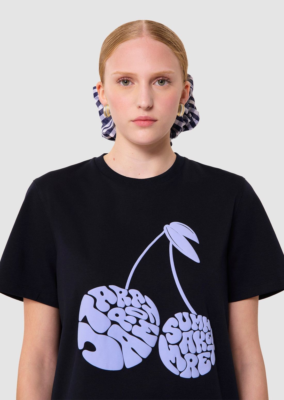 Person wearing a navy t-shirt with a graphic design berries and a navy skirt on a white background