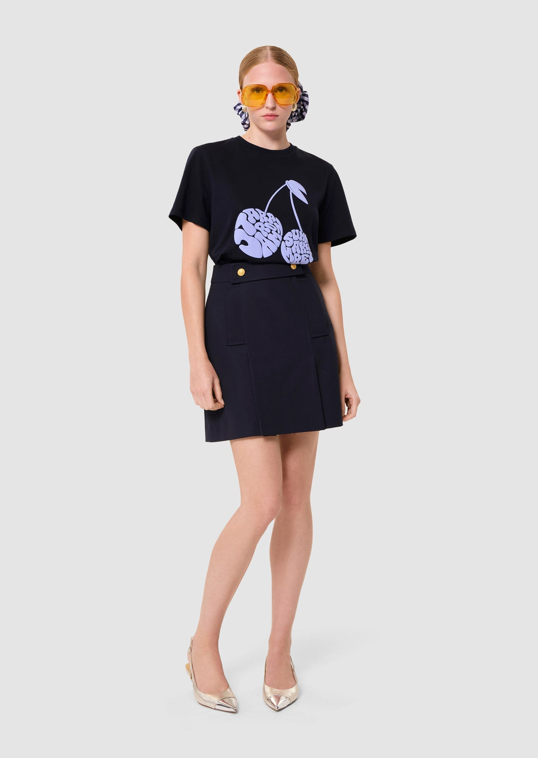Person wearing a navy t-shirt with a graphic design berries and a navy skirt on a white background