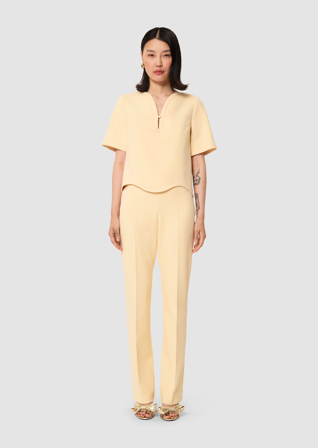 Woman wearing a yellow outfit on a light gray background