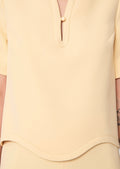 Close-up of a light-yellow blouse with a V-neckline and short sleeves.