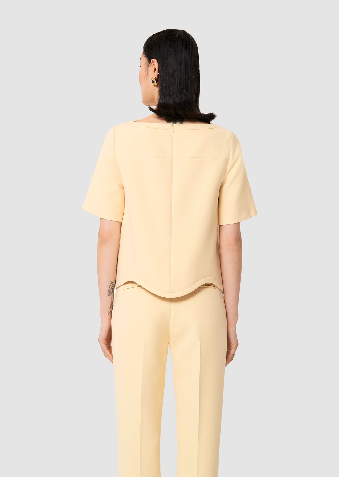 Woman wearing a yellow outfit on a light gray background