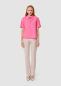 Woman wearing a pink blouse and beige pants on a white background