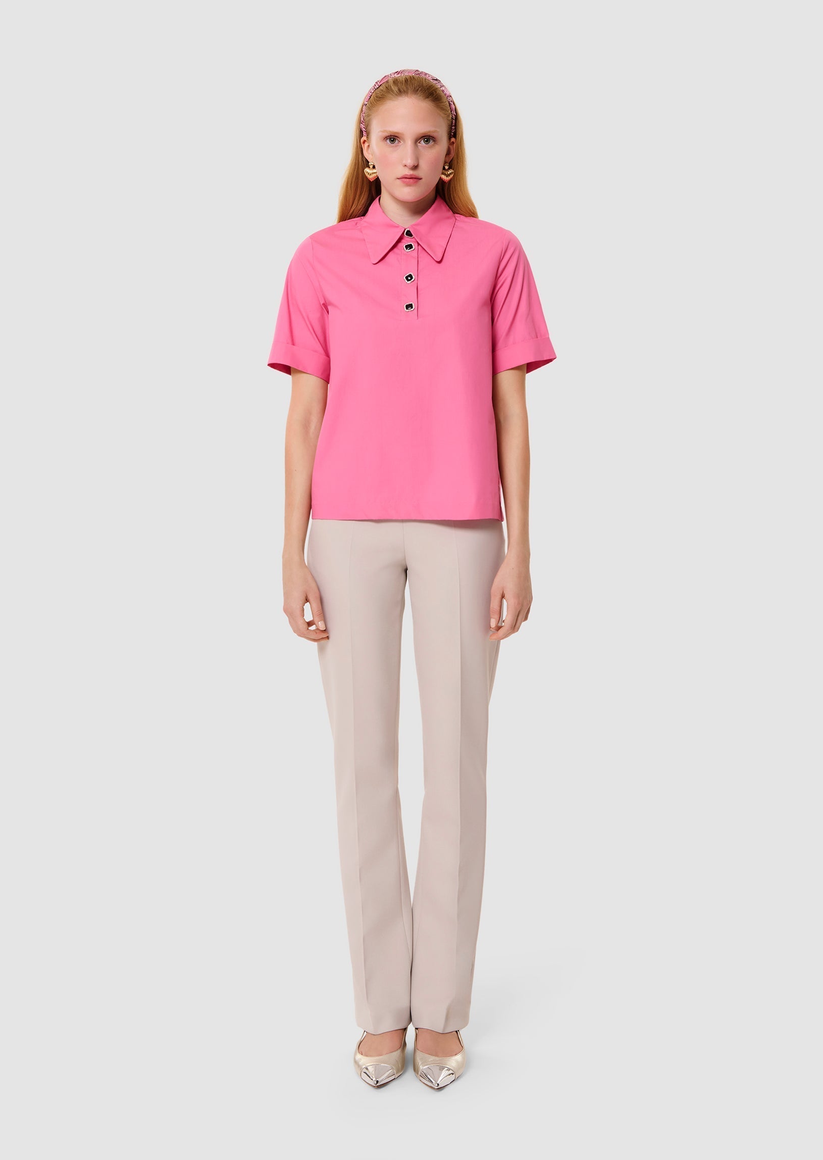 Woman wearing a pink blouse and beige pants on a white background