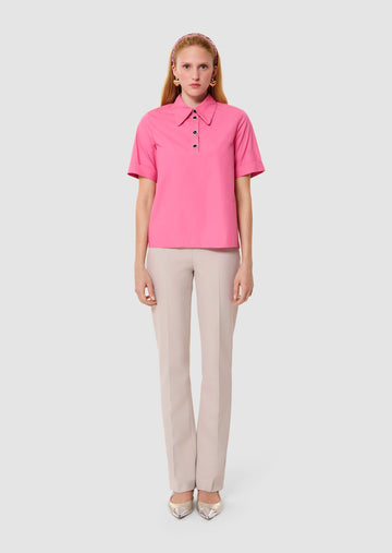 Woman wearing a pink blouse and beige pants on a white background