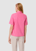 back view of a women wearing a pink blouse with a white background
