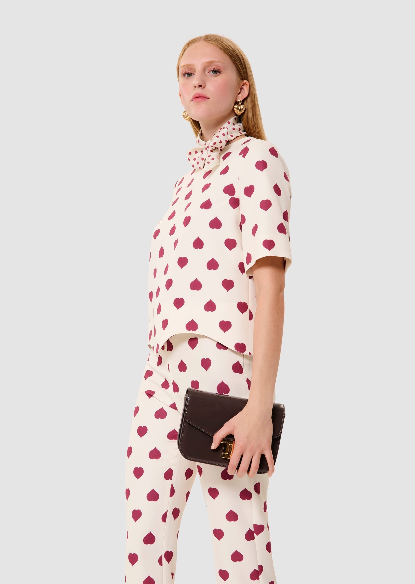 Woman wearing a white outfit with red heart patterns on a plain background