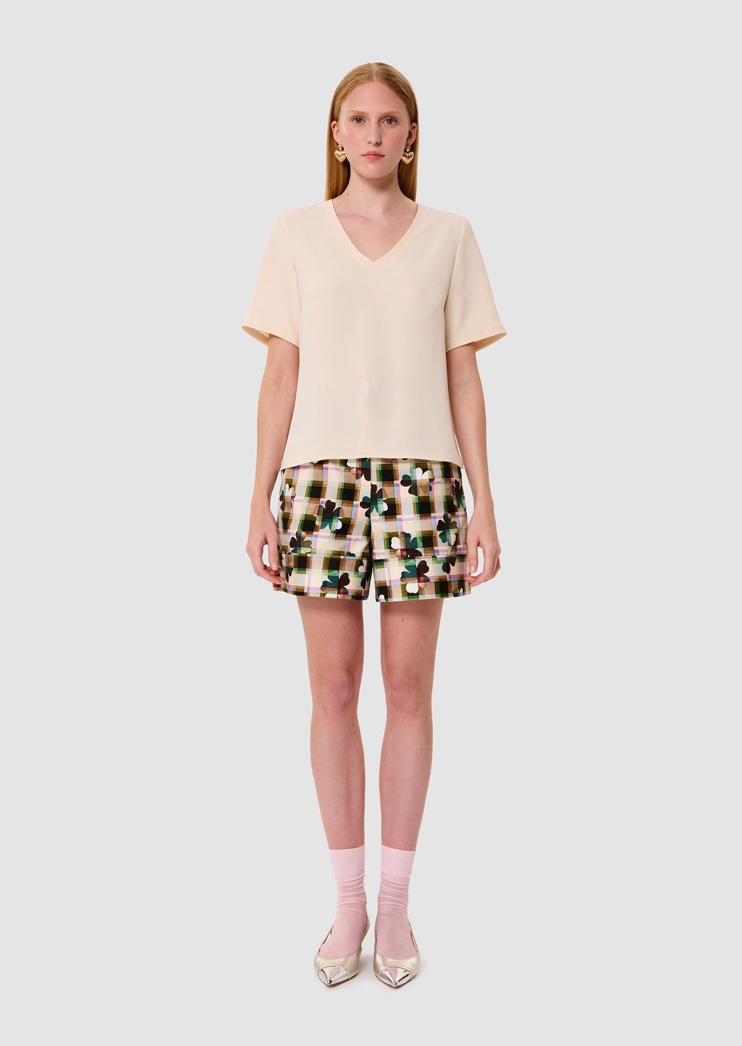 Woman wearing an ecru crepe t-shirt and patterned shorts on a white background