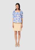 Woman wearing a blue floral blouse and beige skirt on a white background