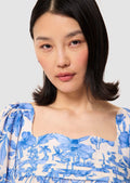 Woman wearing a blue floral blouse against a plain background