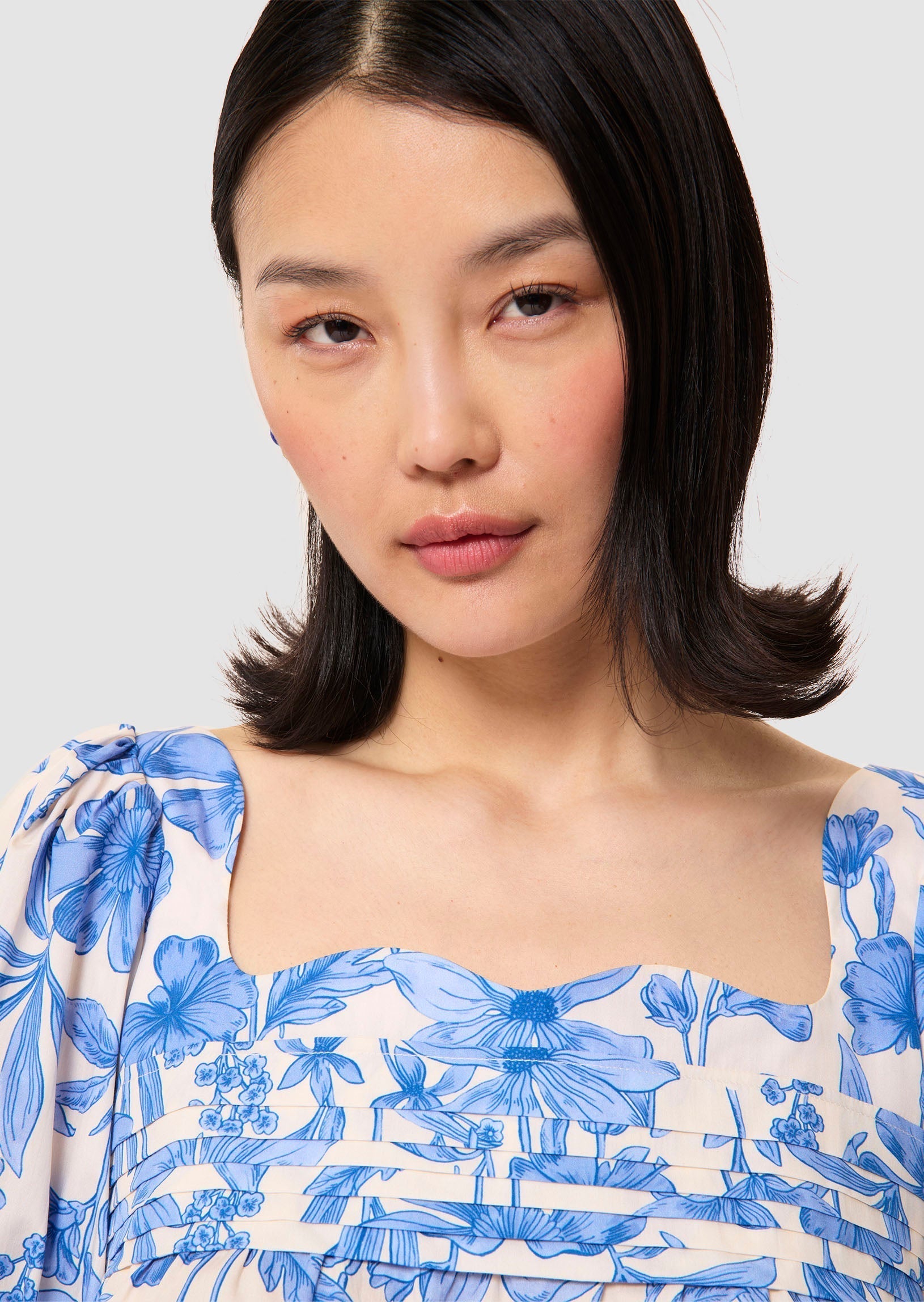 Woman wearing a blue floral blouse against a plain background