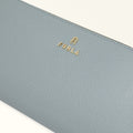 Close-up of a light blue wallet with 'Furla' logo on a white background