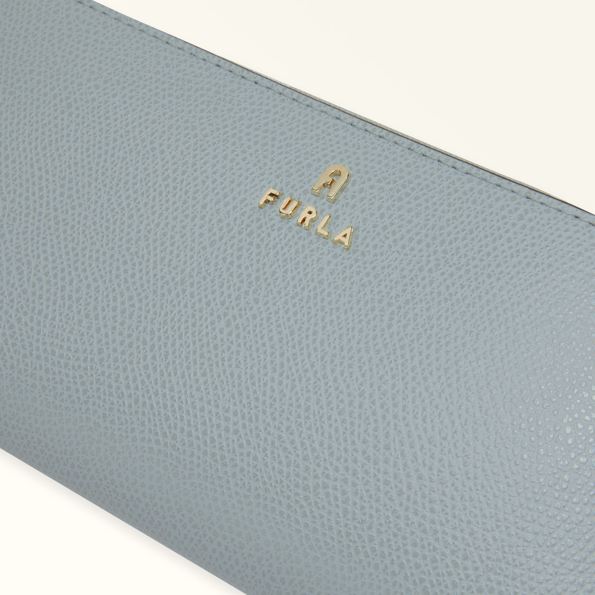 Close-up of a light blue wallet with 'Furla' logo on a white background